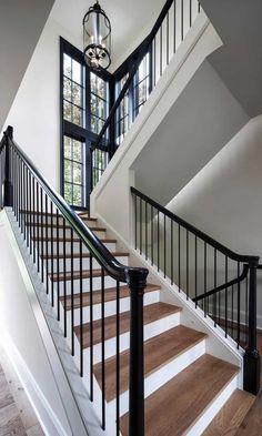 a white staircase with black handrails leading to a second story window and door