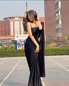 a woman in a black dress is holding an umbrella and posing for the camera with her hand on her head