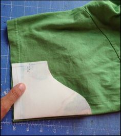 someone is cutting out a piece of fabric to make a jacket with the sleeves folded down