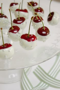 cherries with white and red toppings sit on a glass platter