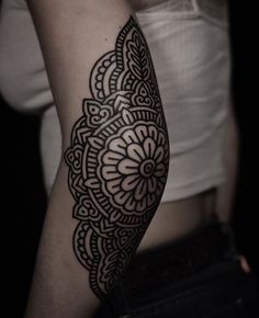 a woman's arm with a black and white tattoo design on her left arm