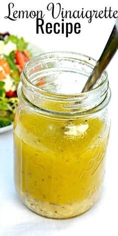 a mason jar filled with lemon vinaigrete recipe next to a salad on a plate