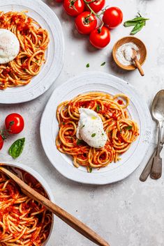 three plates of spaghetti with tomato sauce and mozzarella on the side, next to spoons