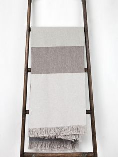 a towel rack with two towels on it and one hanging from the top, in front of a white wall