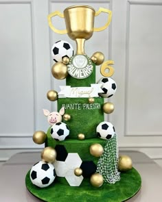 a green cake with soccer balls and a gold cup on top that says, i want it