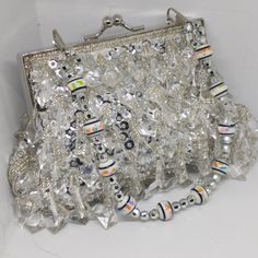 "Vintage Crystal Silver Tone Jewelled Evening Bag 1980s Really Pretty The immaculate condition appears to be gently unused Stunning Ladies' evening handbag with faux glass diamond-shaped crystals throughout and silver sequins Silver-tone chain strap and frame Short top handle strap of porcelain style beads and silver-tone faceted beads Ball clasp closure Great little wedding bag for guest or bride Lined with plain white satin with a single patch interior pocket Perfect with any evening outfit fo Luxury Silver Sequin Bag, Silver Embellished Crystal Clutch, Silver Crystal Beaded Bags, Silver Beaded Crystal Bags, Silver Rectangular Evening Bag With Sequins, Silver Evening Clutch With Bling, Silver Sequined Clutch Evening Bag, Silver Sequined Evening Bag, Silver Embellished Evening Bag For Celebration