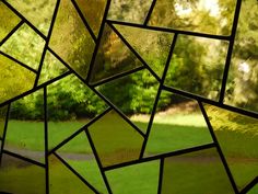 a stained glass window with green grass and trees in the background