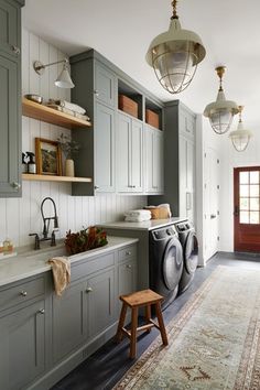 an image of a laundry room with grey cabinets and washer in the middle, next to a white rug