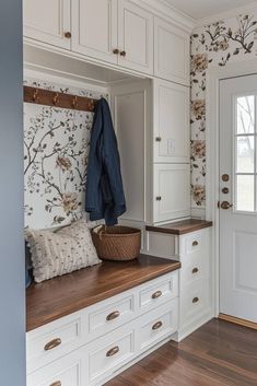 a coat rack and bench in a room with white cabinets, blue walls and wood flooring