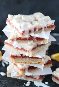 a stack of strawberry shortbreads sitting on top of a black plate next to lemon wedges