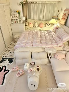 a bed with lots of pillows and stuffed animals on the floor next to each other