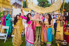 three women in colorful dresses holding umbrellas and posing for the camera at a wedding