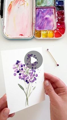 someone is painting flowers with watercolors on paper