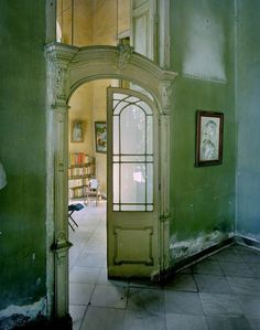 an open door leading into a room with green walls and tile flooring on either side