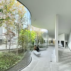 two people sitting on a bench in the middle of a room with large glass walls