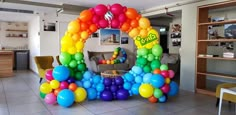 an arch made out of balloons in the middle of a room with tables and chairs