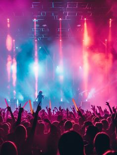 a concert scene with people on stage and lights in the background, some holding up their hands