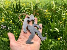 a person holding up a metal object in the middle of a field with wildflowers