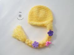 a crocheted yellow hat with flowers on the brim is laying next to it