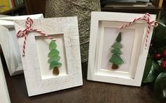 two frames with christmas trees in them on a table