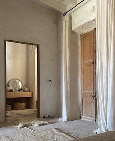 a room with a bed, mirror and door that is partially covered in white fabric