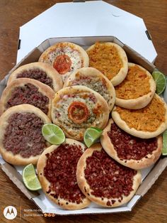 an open box filled with different types of pizzas on top of a wooden table