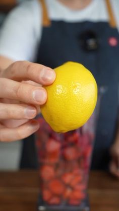 a person holding an orange in front of a blender