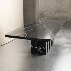 a black and white marbled table in an empty room with concrete walls behind it