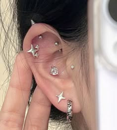 a woman's ear with three silver stars on it and two piercings in the middle