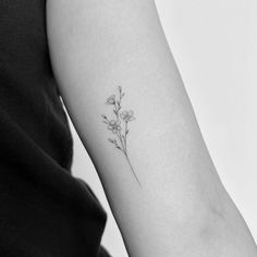 a small flower tattoo on the left inner arm and shoulder is shown in black and white