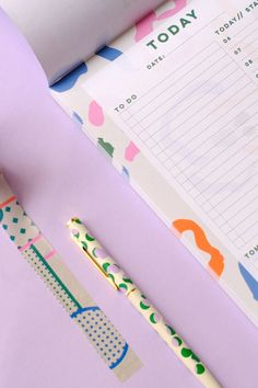 a close up of a pen and paper on a purple surface with a notepad