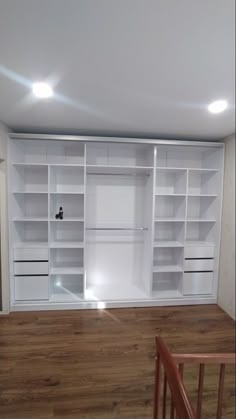 an empty room with white shelves and wooden floors