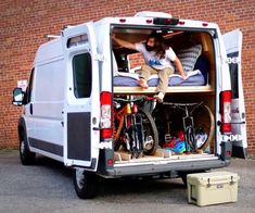 a man sitting in the back of a van with his bike on it's bed