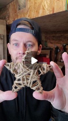 a man is holding up a starfish made out of string and wood, with his hands in front of him