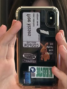 someone holding up their cell phone case with stickers all over the back and sides