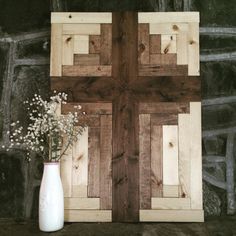 a vase with some flowers in it next to a wooden cross