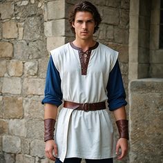 a man dressed in roman clothing standing next to a stone wall