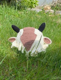 a stuffed cow laying in the grass with it's head up to its side