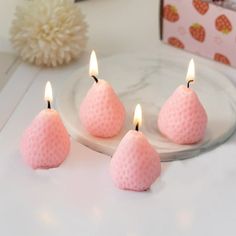 three pink candles sitting on top of a white plate next to a box of candy