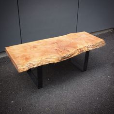 a wooden bench sitting on top of a black metal frame sidewalk next to a building