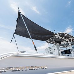 a white boat with a black flag on the front is parked in the sand under a blue sky