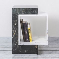 a book shelf with books on top of it next to a white wall and wooden floor