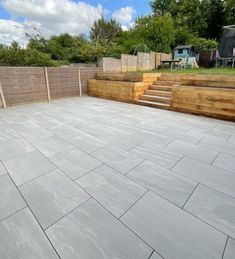 an empty patio with steps leading up to the back yard and wooden fenced in area