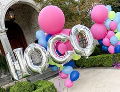 balloons spelling out the word boo spelled out in front of a house with hedges and bushes