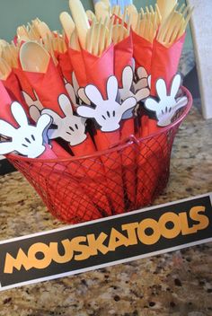 mickey mouse napkins are in a red basket on the counter next to a sign that says mouskatools