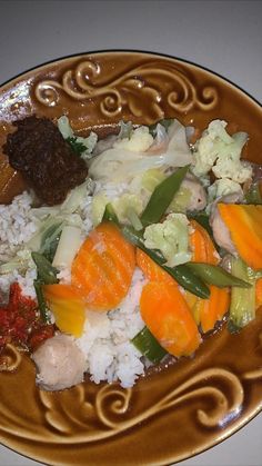 a brown plate topped with rice and veggies on top of a white table