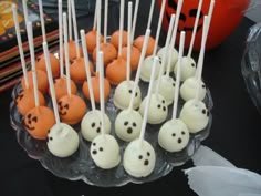 halloween cake pops with white frosting and chocolate sprinkles on sticks in a clear bowl