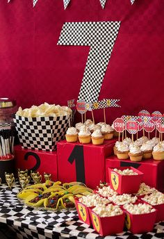 a table topped with lots of cupcakes and cake next to a number seven sign