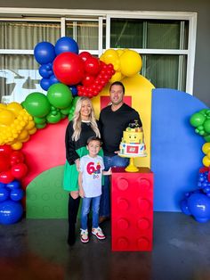 a man and woman standing next to a child with a birthday cake in front of them