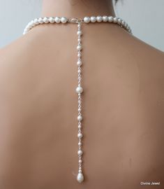 the back of a woman's head wearing a white necklace with pearls on it